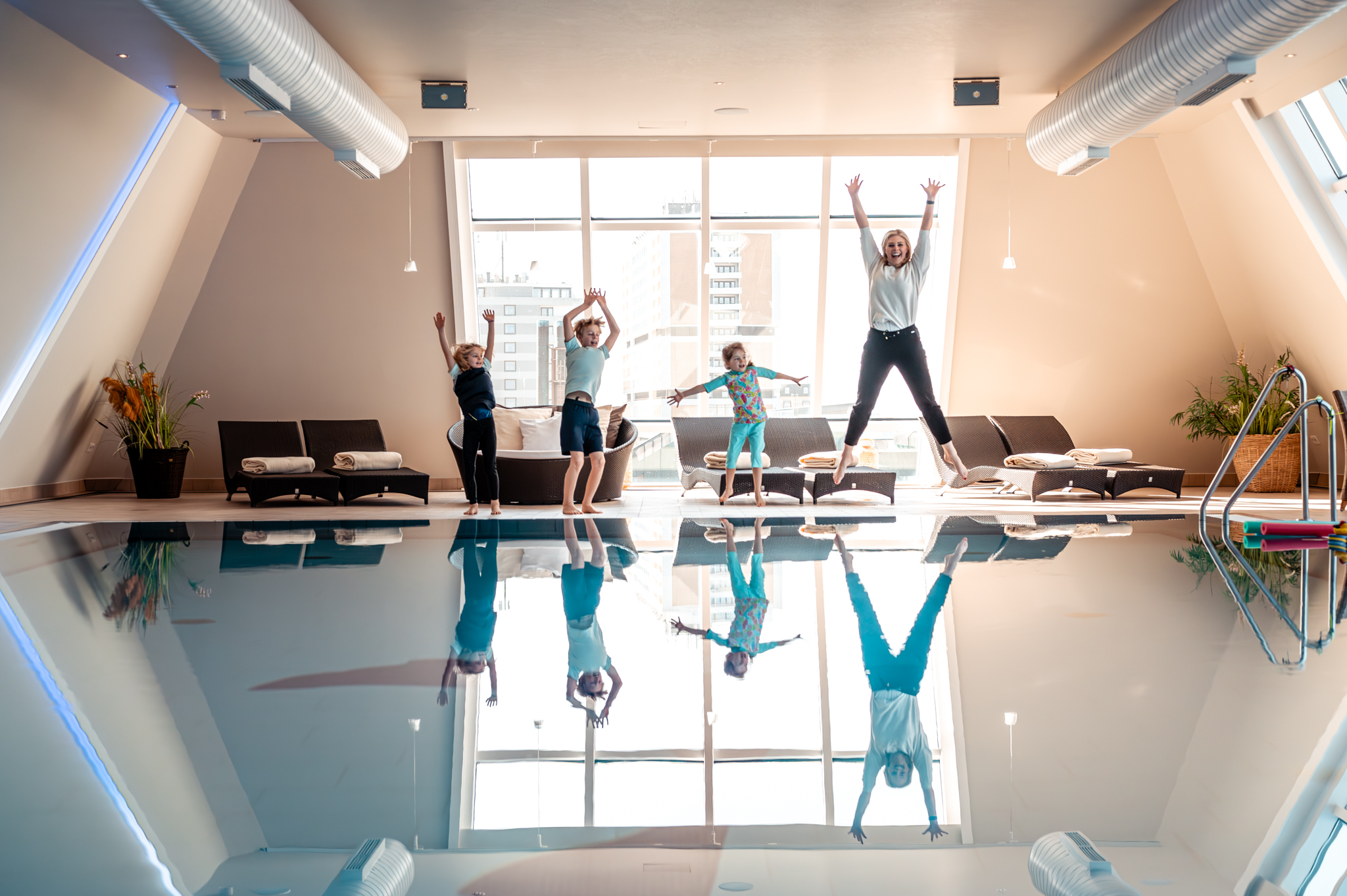 Schwimmtrainerin springt mit Kindern am Hotelpool in die Luft